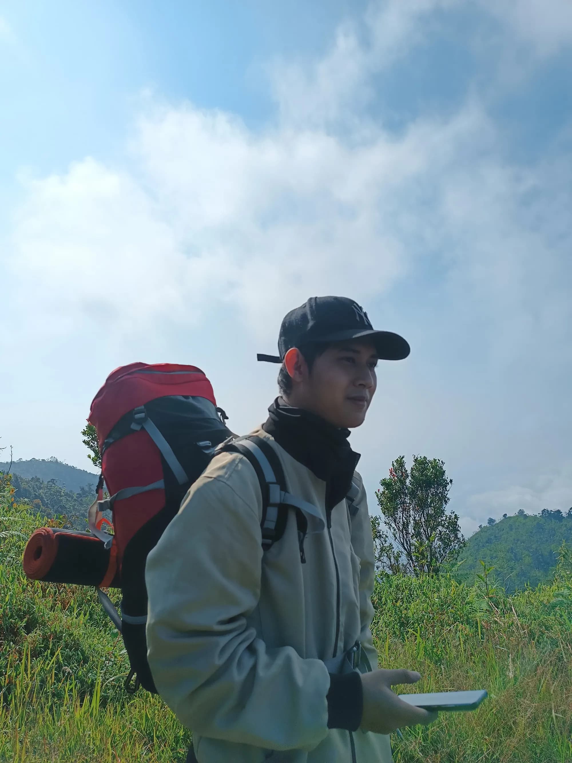 Muhammad Daffa on a mountain hike, backpack on, looking out over the ridge